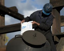 Crew member empties bagged sand into a locomotive sand dome