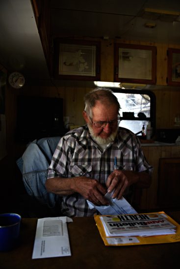 Bill Bemis opening mail in his home-built RV; Sublette, CO
